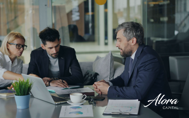 cTime pequeno em discussão técnica, com laptop aberto e papéis espalhados sobre crédito colateralizado